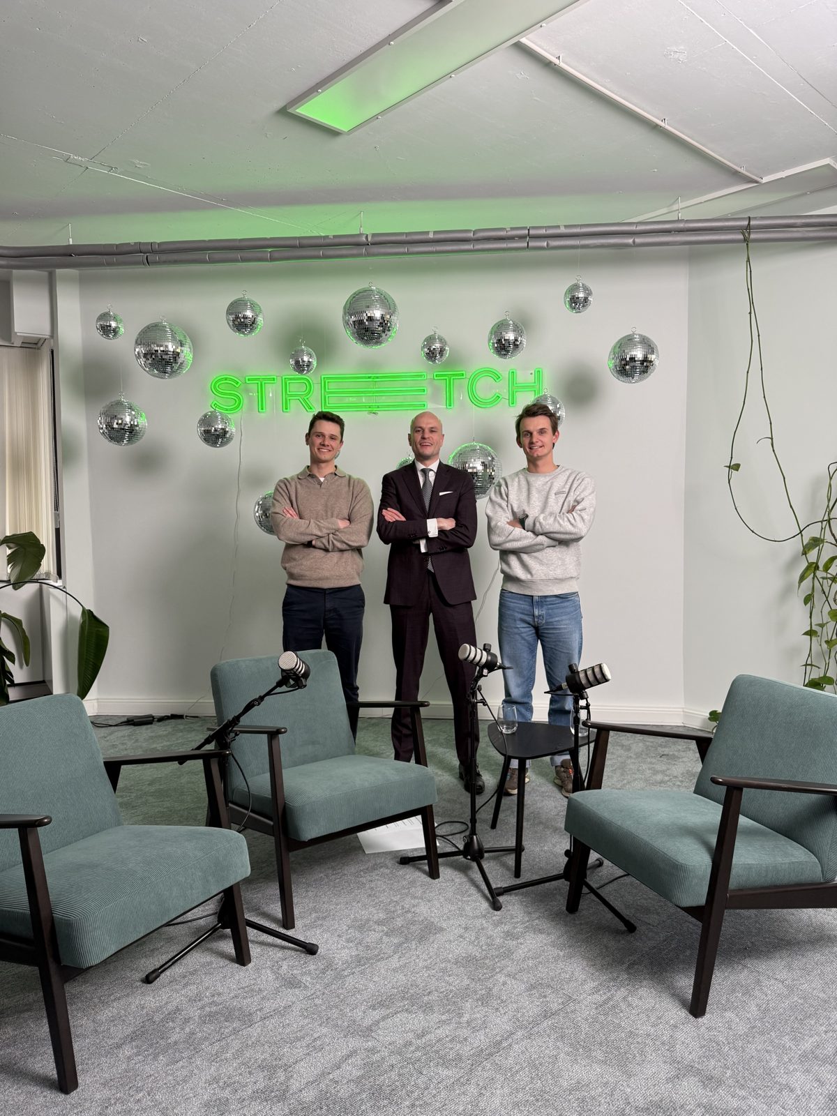 The two hosts and Ben Swerts in front of the Stretch neon sign after the recording